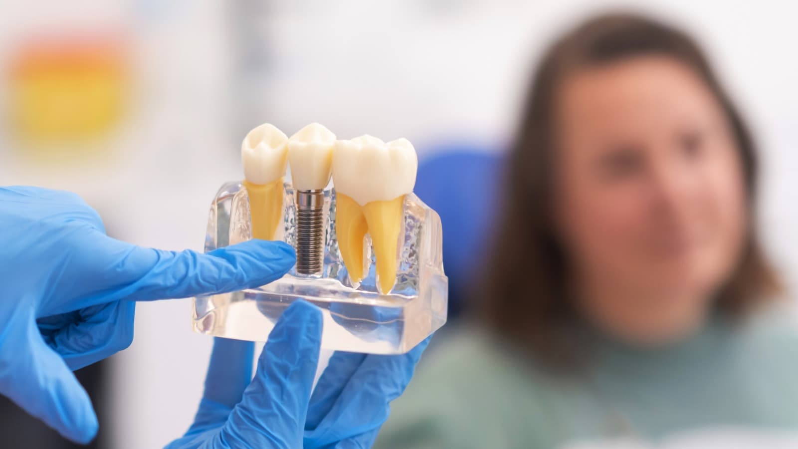 Dentist showing a dental implant model — titanium post and porcelain crown — at Dr. Mukesh's Dental Solutions, Kothrud Pune