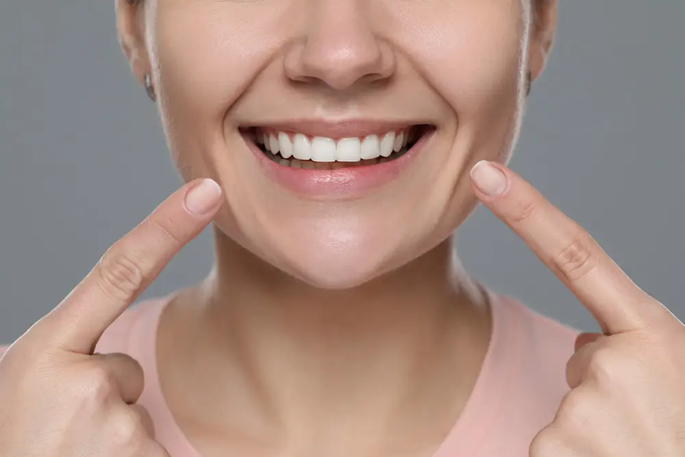 Woman pointing to her balanced, corrected smile after gummy smile treatment