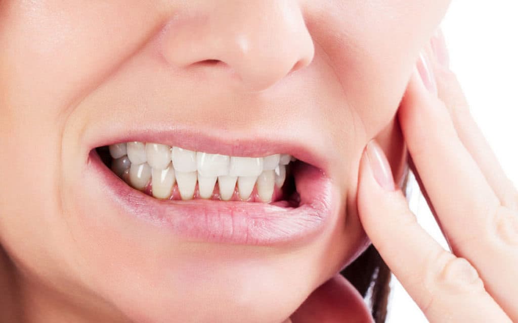 Woman holding her jaw in discomfort from teeth grinding and bruxism